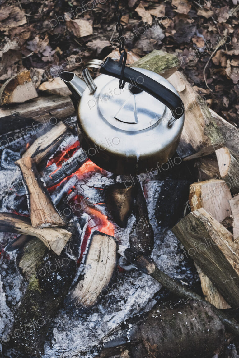 High angle close up of metal kettle hanging over a campfire.
