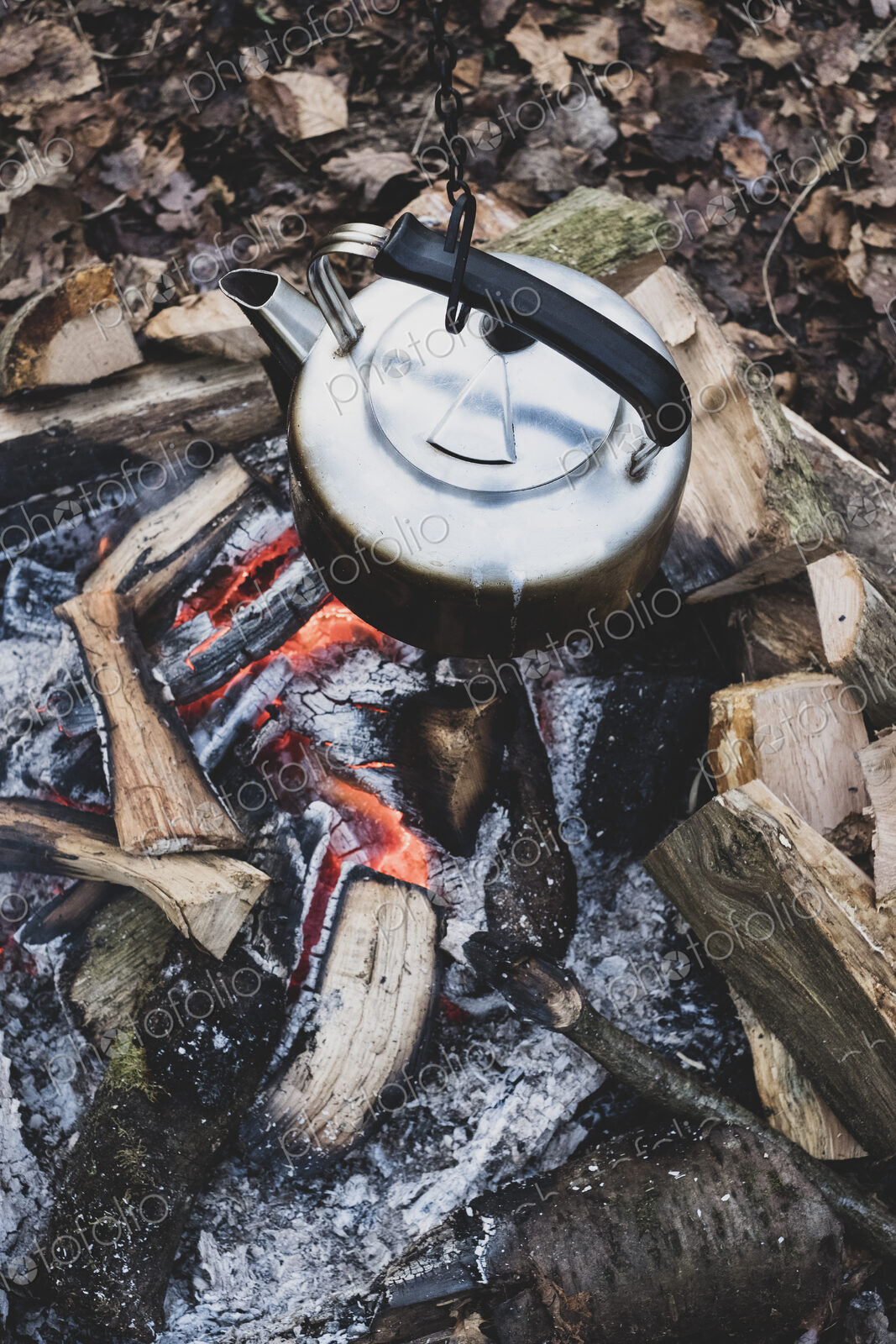 High angle close up of metal kettle hanging over a campfire.