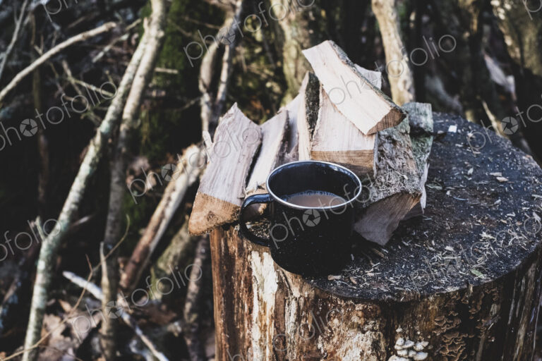 High angle close up of mug of tea and wooden logs on chopping block.
