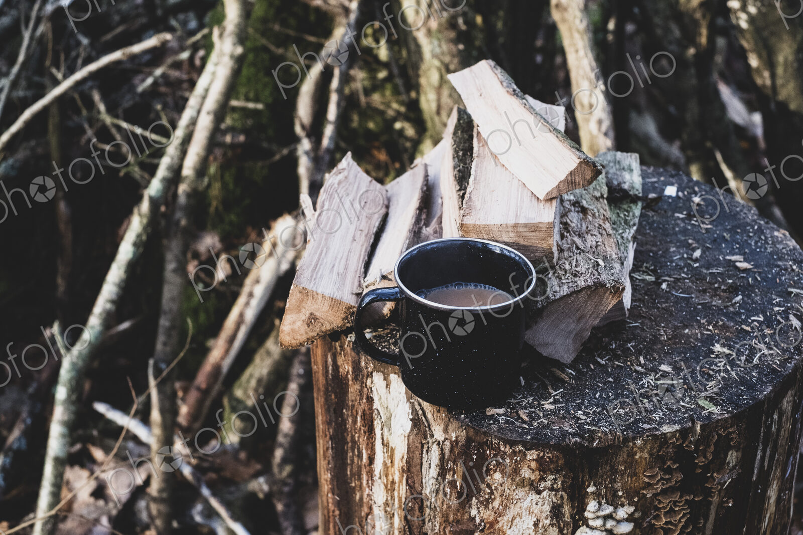 High angle close up of mug of tea and wooden logs on chopping block.