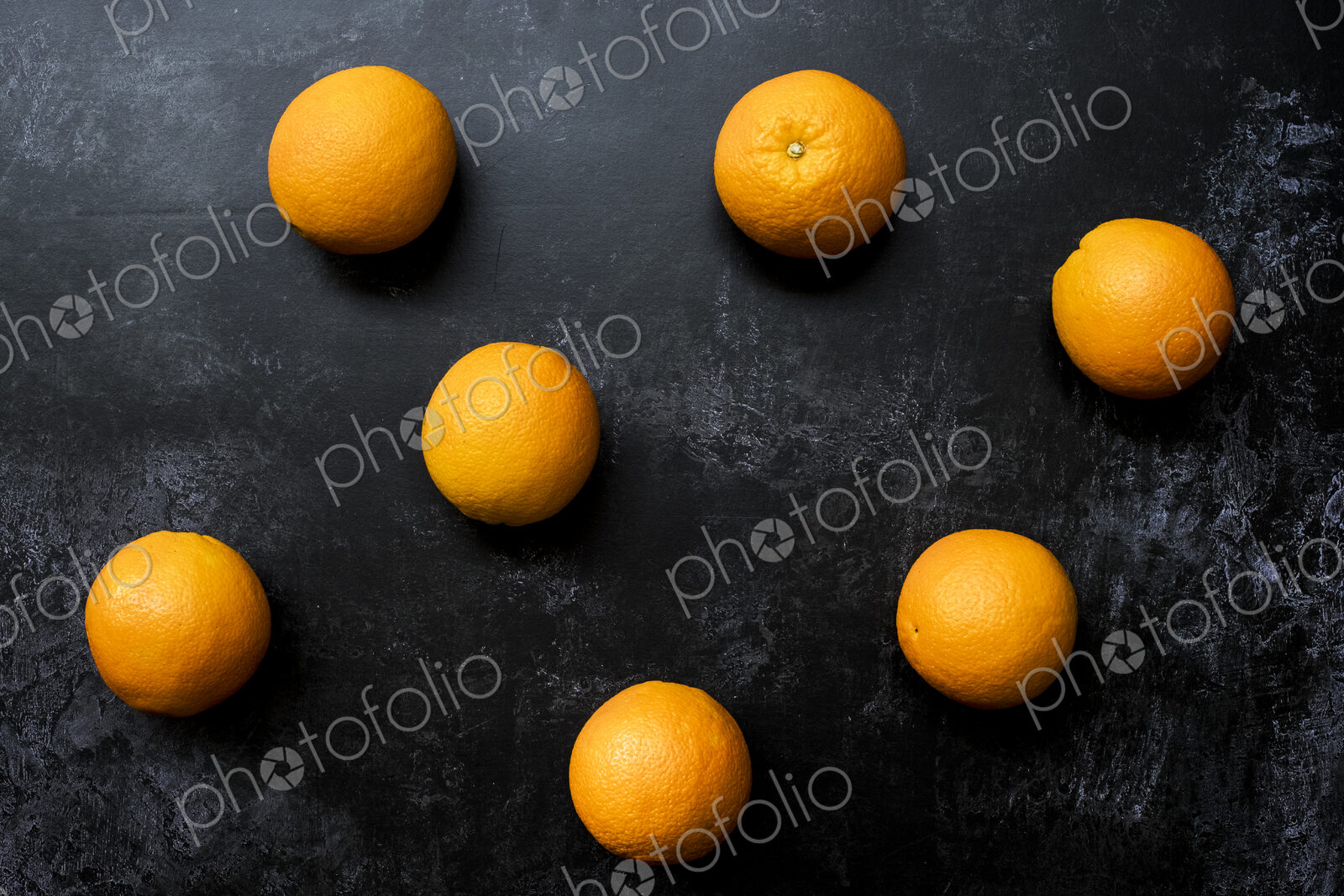 High angle close up of oranges on black background.