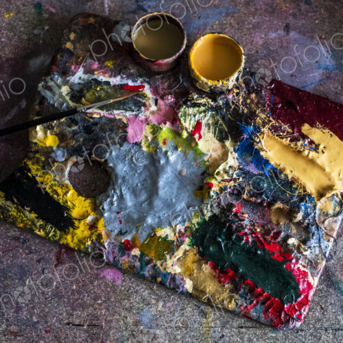High angle close up of painter's palette, oil paints and paintbrush in a workshop. High angle close up of painter's palette, oil paints and paintbrush in a workshop.