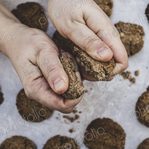 High angle close up of person breaking freshly baked chocolate cookie in half. High angle close up of person breaking freshly baked chocolate cookie in half.