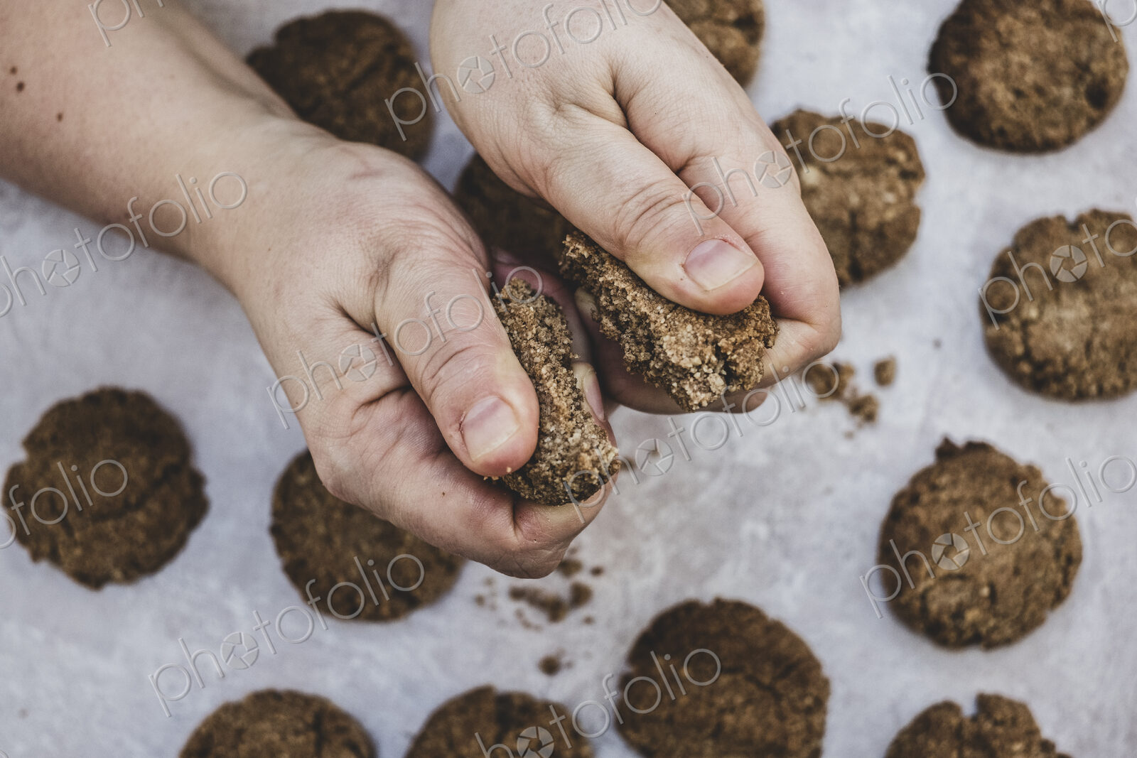 High angle close up of person breaking freshly baked chocolate cookie in half.