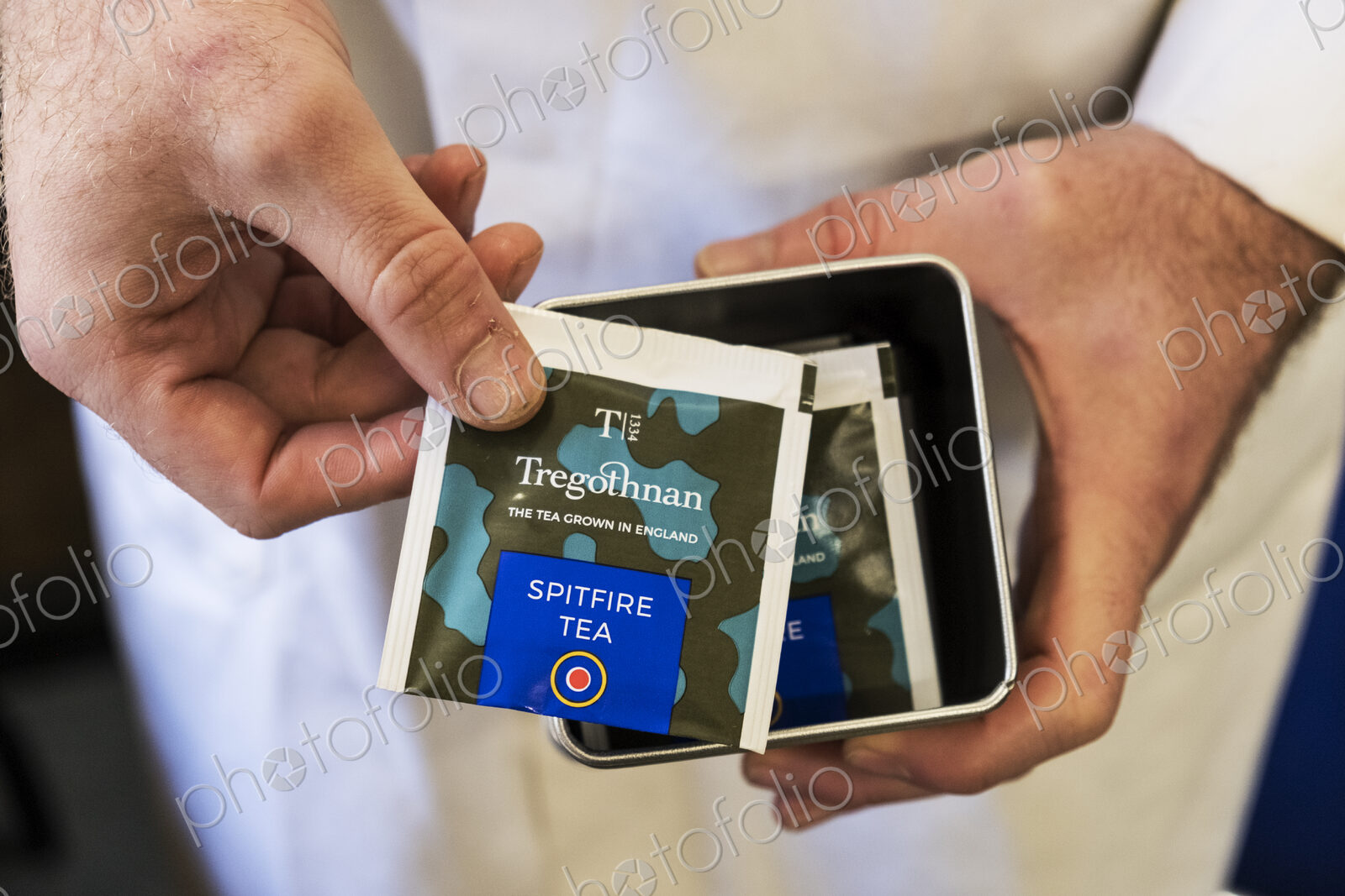 High angle close up of person holding a tin with tea bags.
