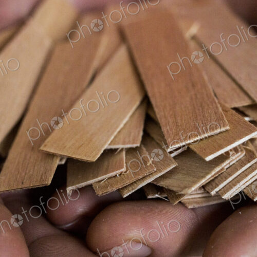 High angle close up of person holding bunch of wooden candle wicks. High angle close up of person holding bunch of wooden candle wicks.