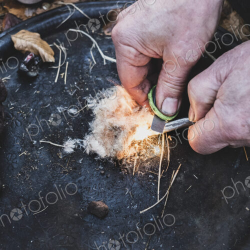 High angle close up of person igniting tinder to start a campfire.
