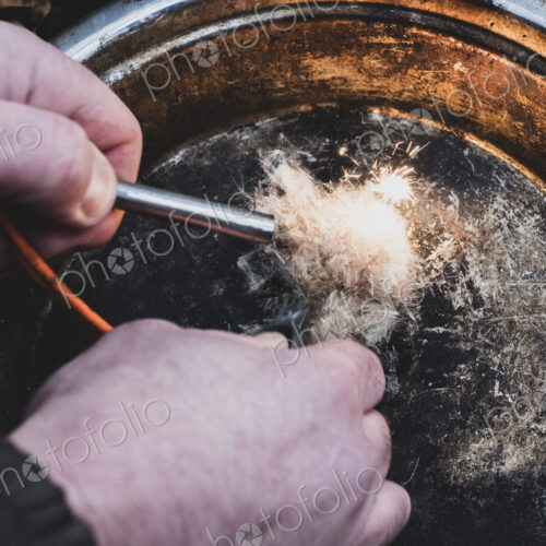 High angle close up of person igniting tinder to start a campfire.