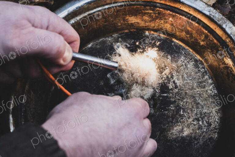 High angle close up of person igniting tinder to start a campfire.
