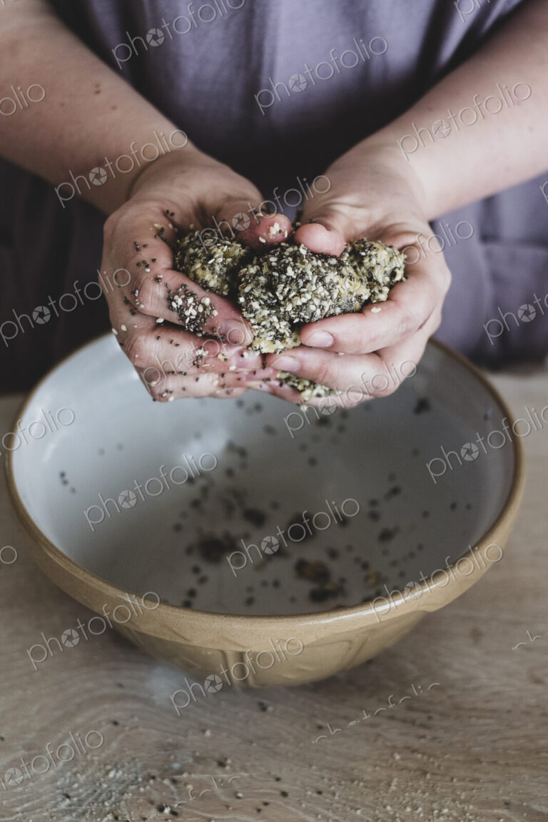 High angle close up of person kneading dough over mixing bowl.