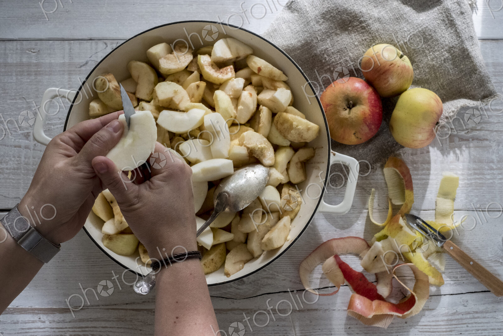 High angle close up of person placing apples in a round baking tin.