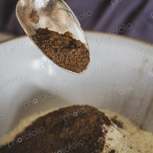 High angle close up of person pouring cocoa powder into mixing bowl with baking…