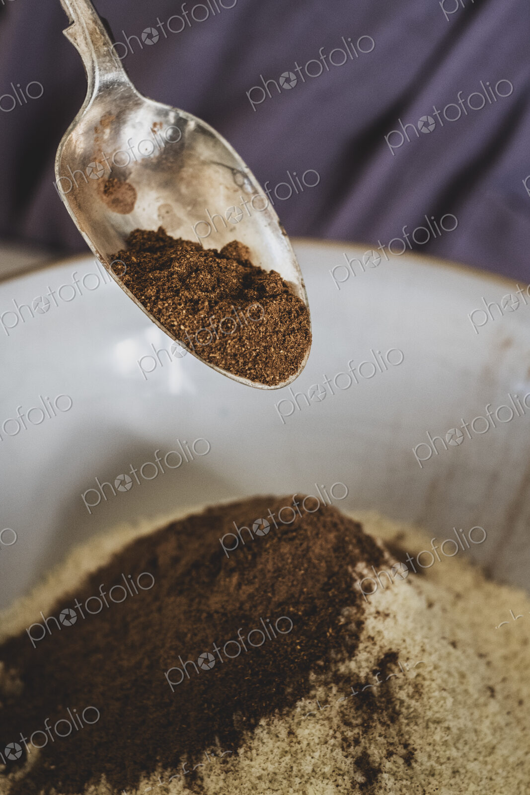 High angle close up of person pouring cocoa powder into mixing bowl with baking…