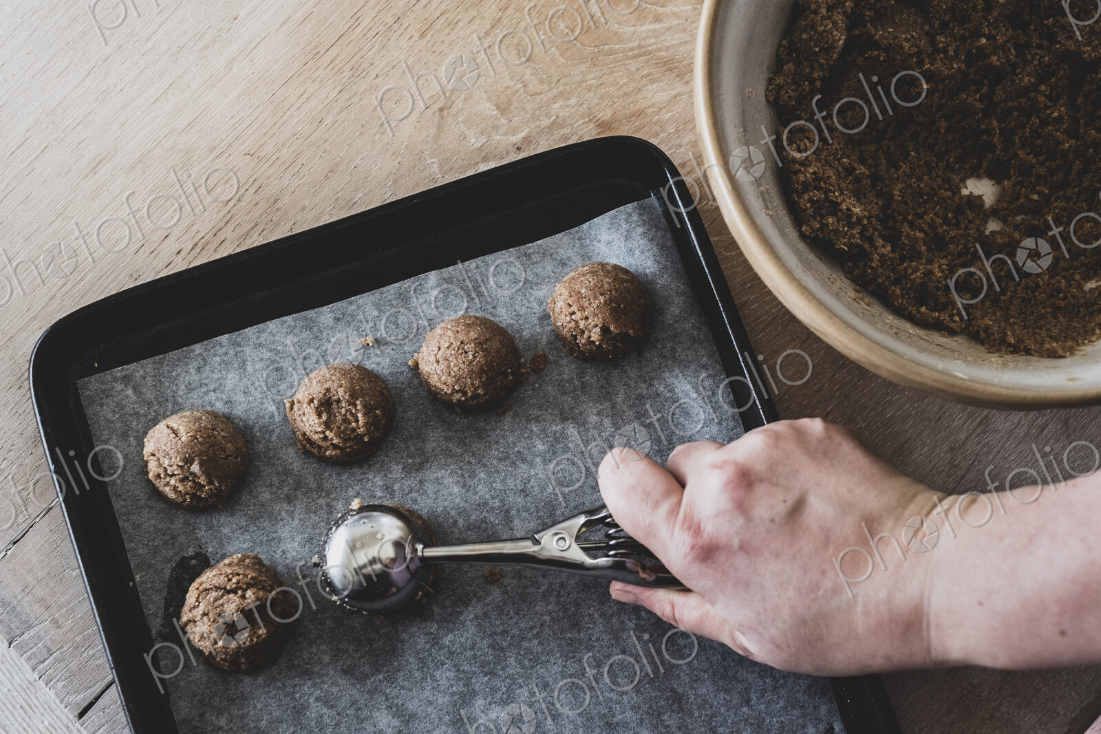 High angle close up of person putting chocolate cookie dough on a baking tray.