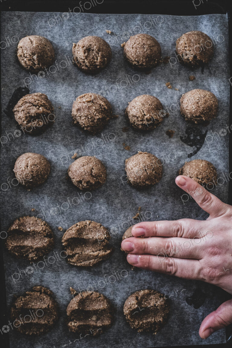 High angle close up of person putting chocolate cookie dough on a baking tray.