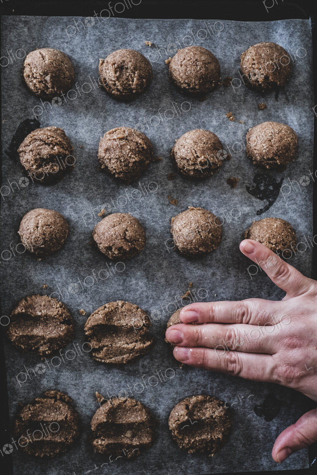 High angle close up of person putting chocolate cookie dough on a baking tray.
