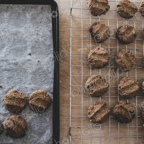 High angle close up of person removing freshly baked chocolate cookies from a baking tray. High angle close up of person removing freshly baked chocolate cookies from a baking tray.