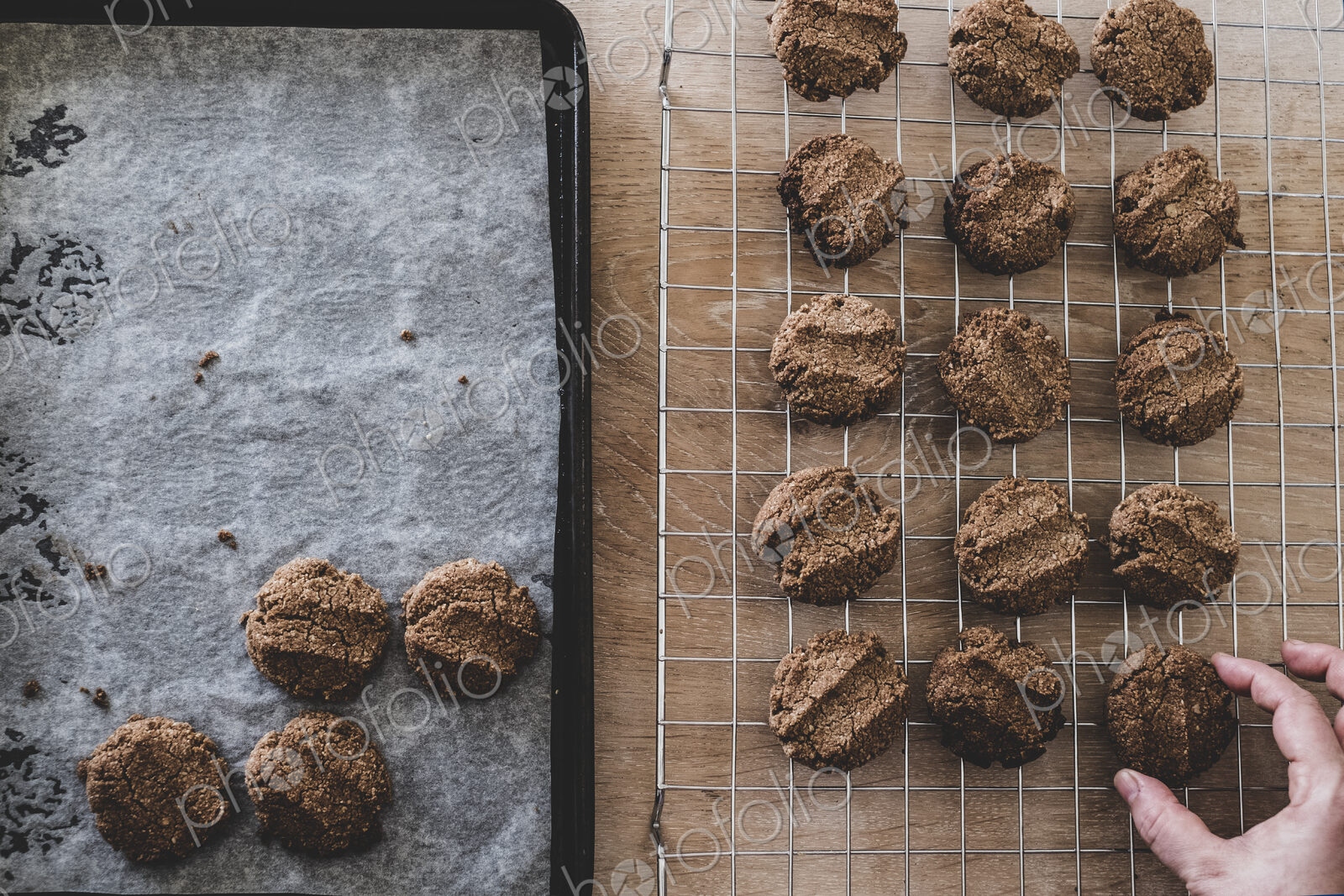 High angle close up of person removing freshly baked chocolate cookies from a baking tray.