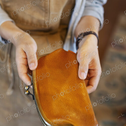 High angle close up of person standing in a leather shop, holding an leather purse.