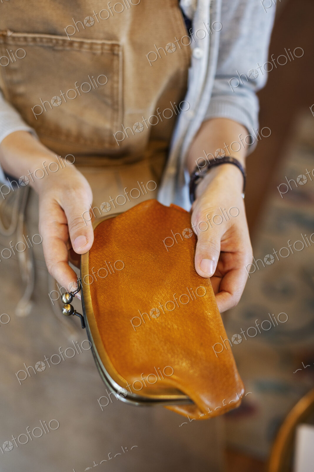 High angle close up of person standing in a leather shop, holding an leather purse.