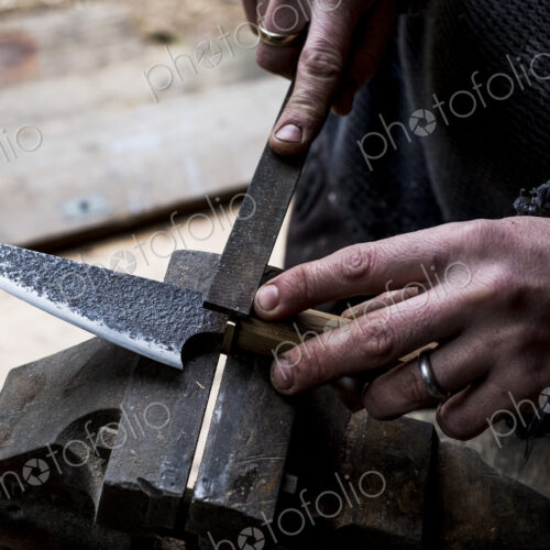 High angle close up of person working on handmade knife using a file. High angle close up of person working on handmade knife using a file.