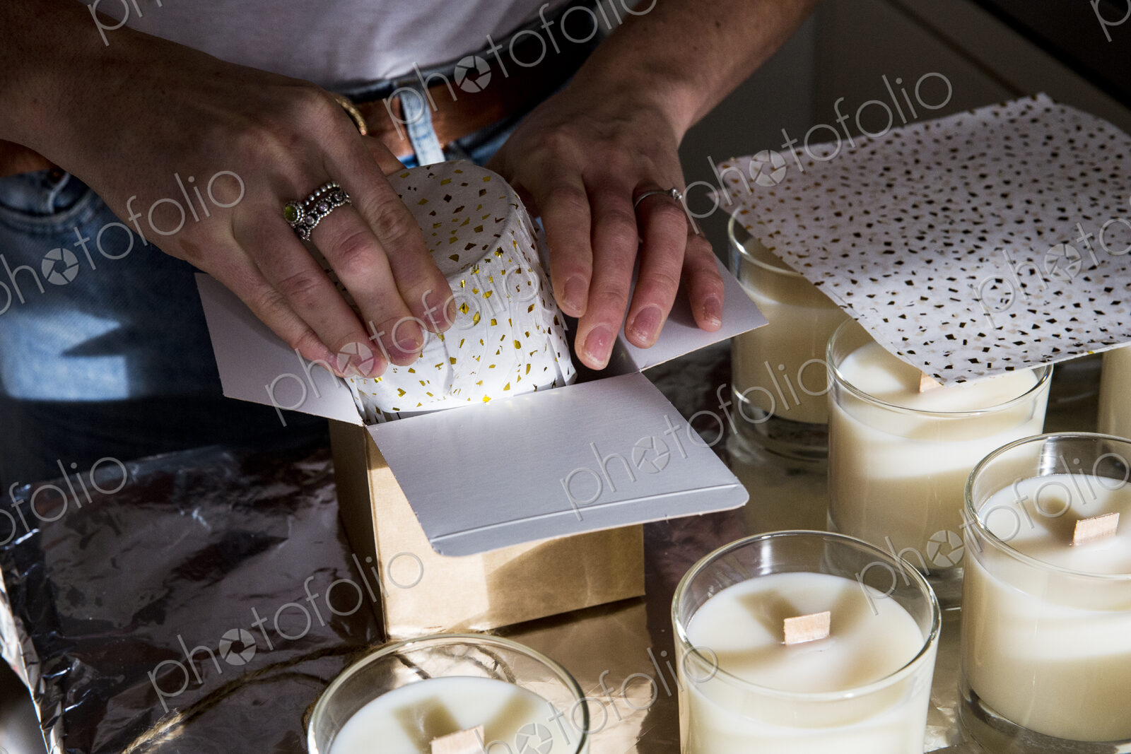 High angle close up of person wrapping handmade white jar candles.