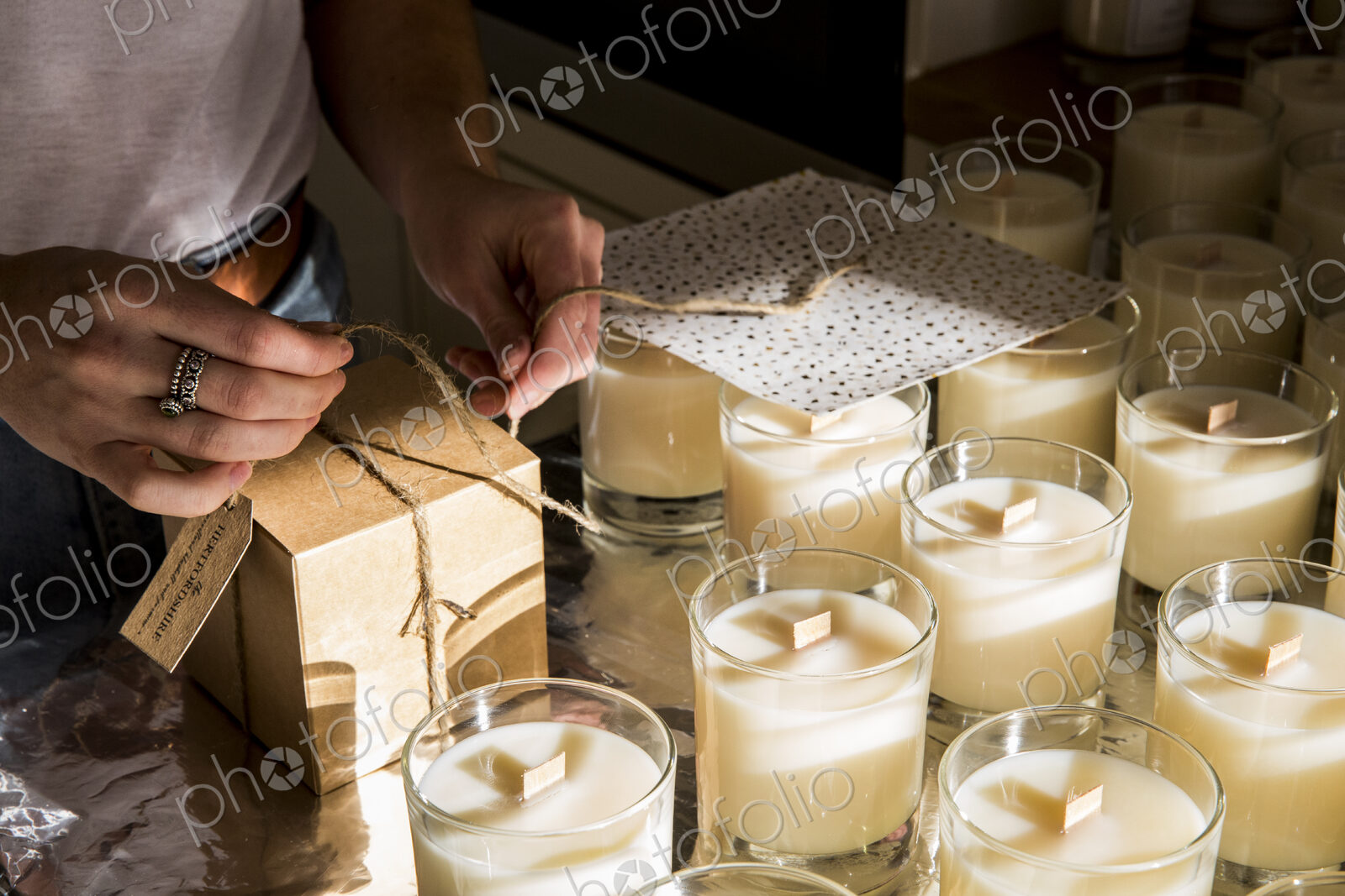 High angle close up of person wrapping handmade white jar candles.