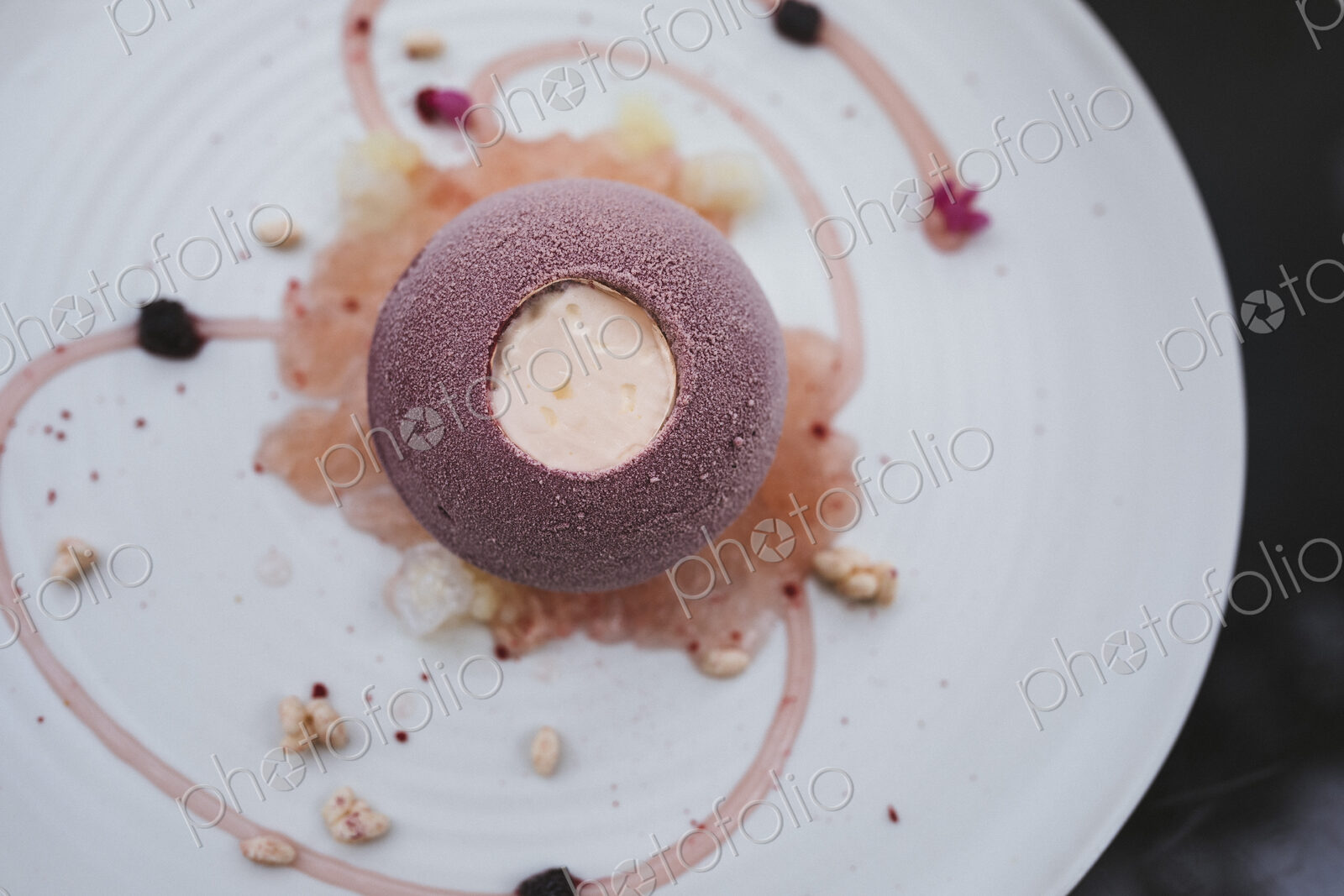 High angle close up of plate of dessert with with a cassis bombe and elderflower…