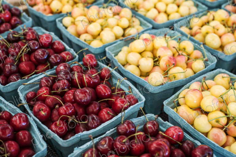 High angle close up of punnets with fresh red and yellow cherries at a fruit and…