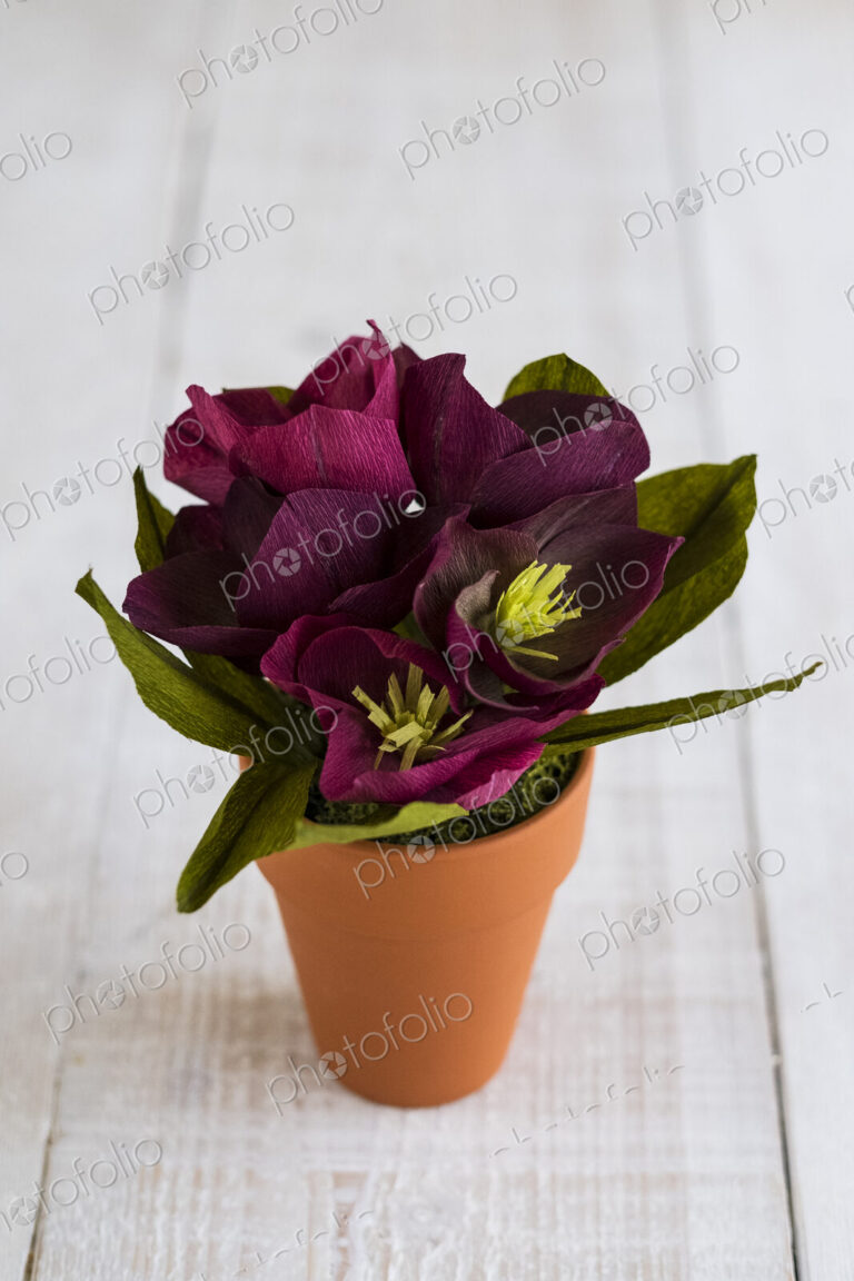 High angle close up of purple paper flowers in a terracotta flowerpot.