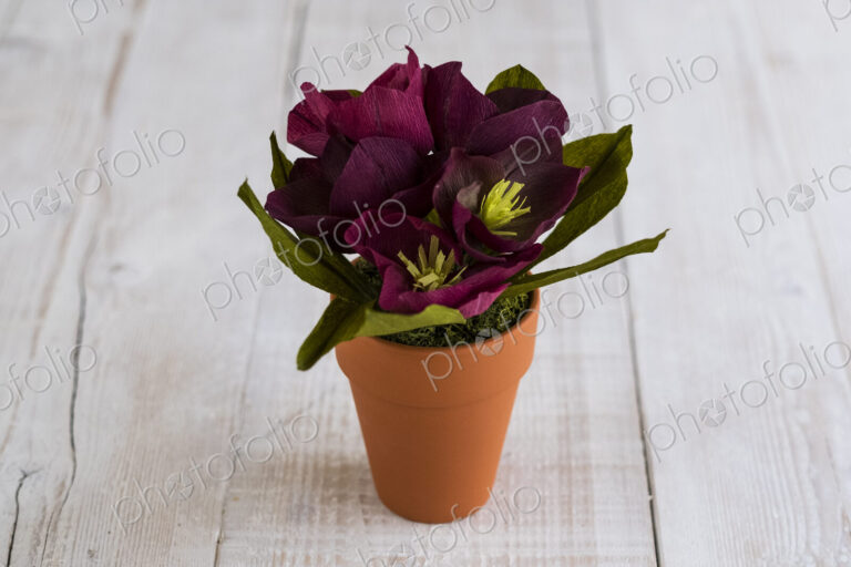 High angle close up of purple paper flowers in a terracotta flowerpot.