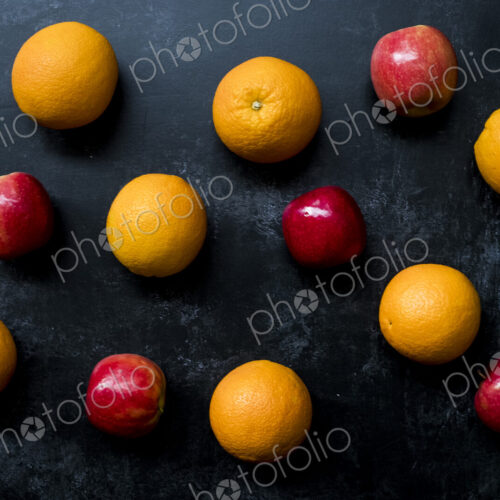 High angle close up of red apples and oranges on black background. High angle close up of red apples and oranges on black background.