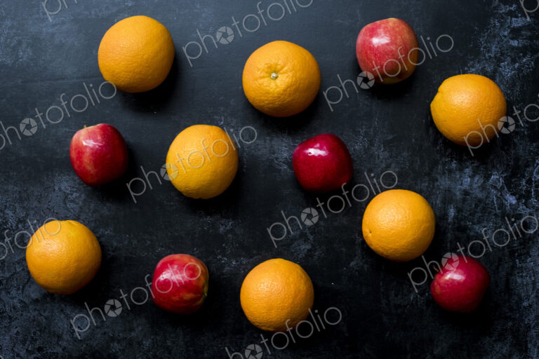 High angle close up of red apples and oranges on black background.