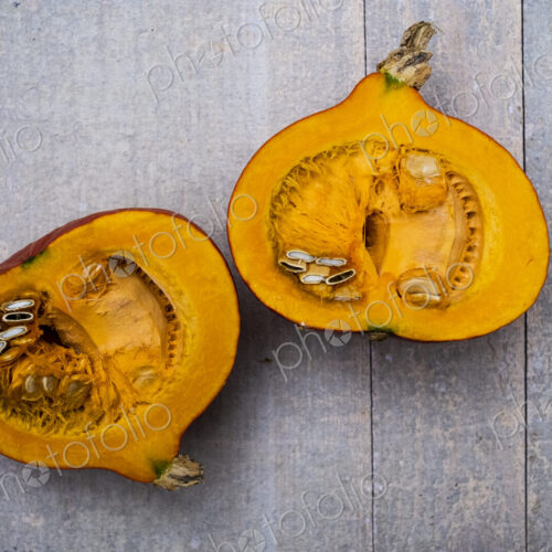 High angle close up of red pumpkin with orange flesh cut in half. High angle close up of red pumpkin with orange flesh cut in half.