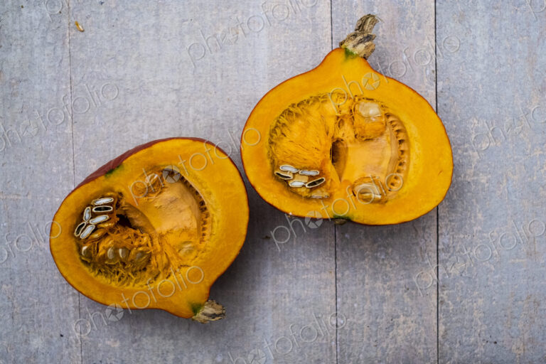 High angle close up of red pumpkin with orange flesh cut in half.