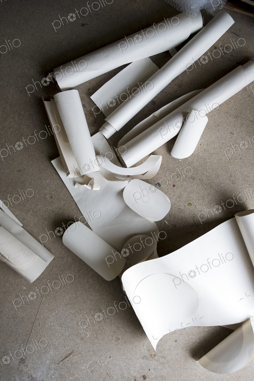 High angle close up of rolls and cut-offs of stiff rolled drawing paper.