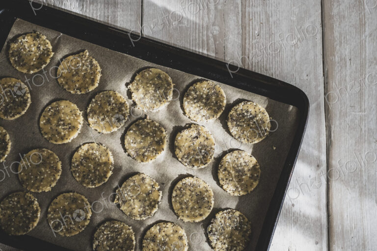 High angle close up of seeded cracker dough on a baking tray.