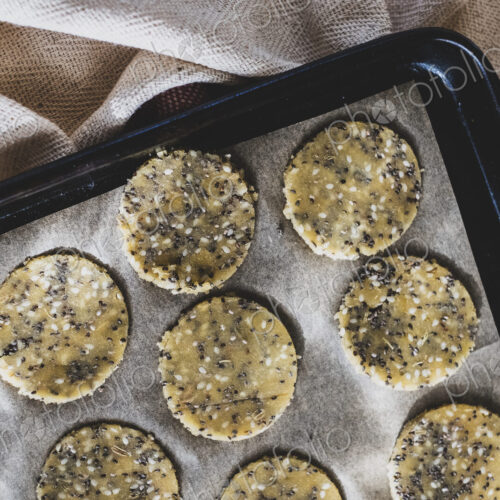 High angle close up of seeded cracker dough on a baking tray. High angle close up of seeded cracker dough on a baking tray.