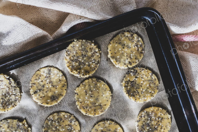 High angle close up of seeded cracker dough on a baking tray.