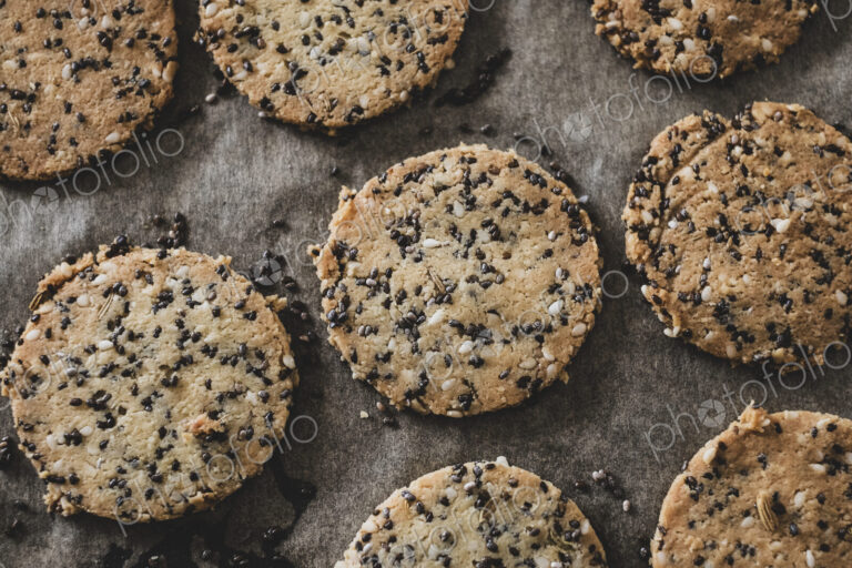 High angle close up of seeded cracker dough on a baking tray.