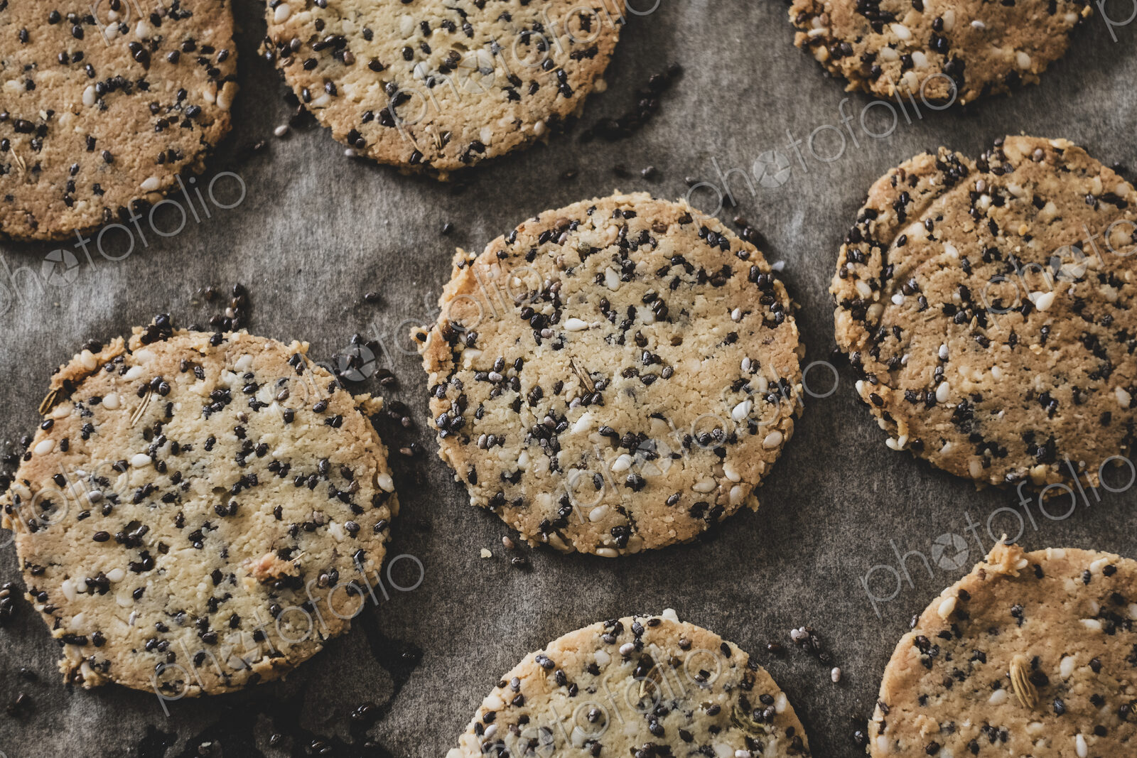 High angle close up of seeded cracker dough on a baking tray.