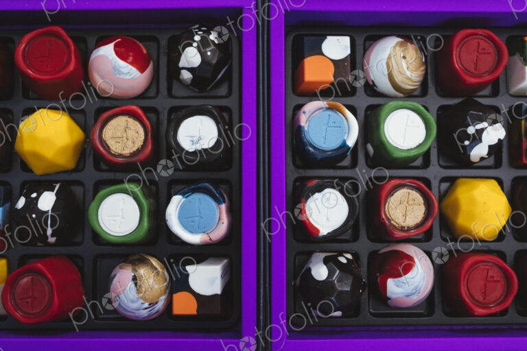 High angle close up of selection of bonbons in a purple and black box.