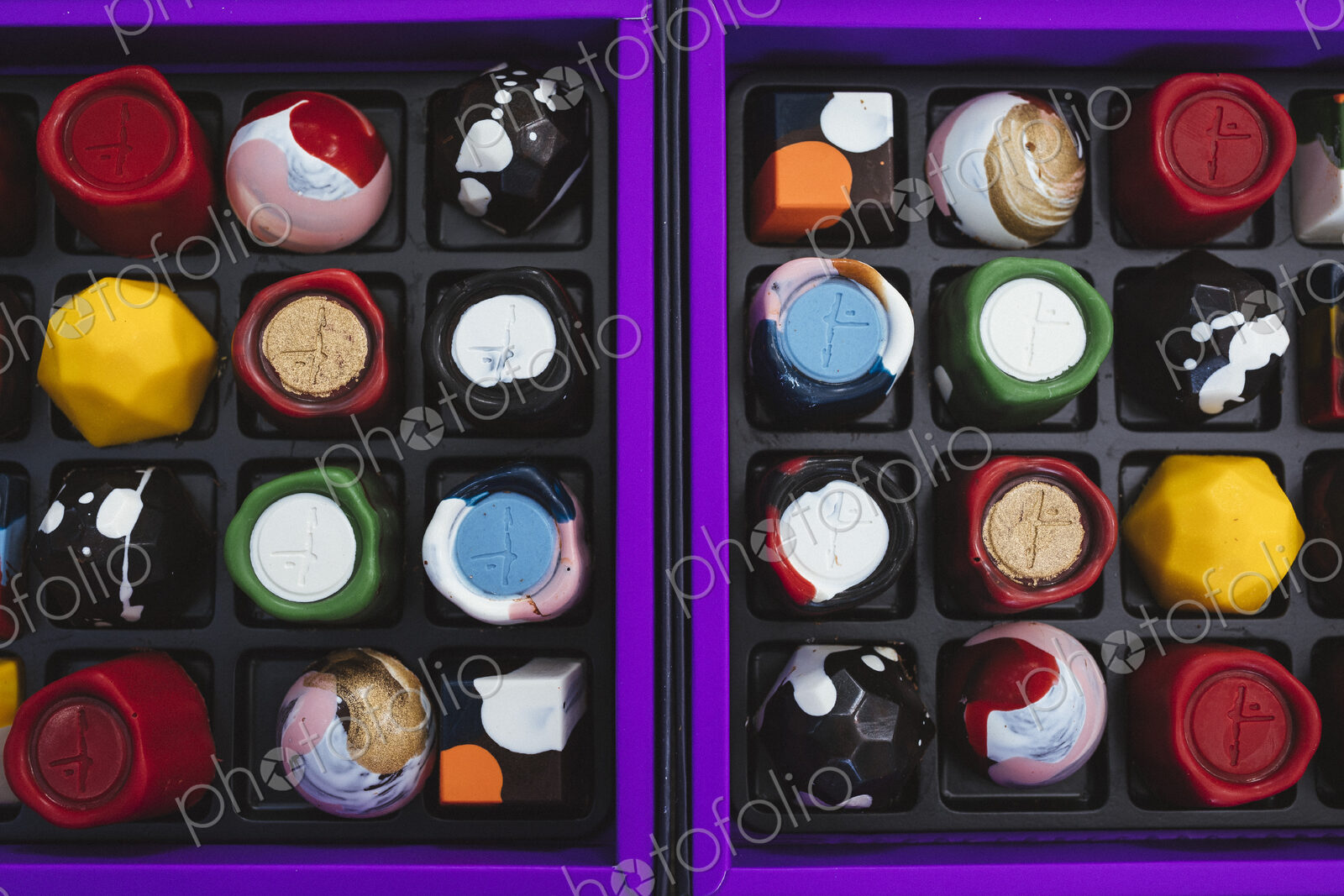 High angle close up of selection of bonbons in a purple and black box.
