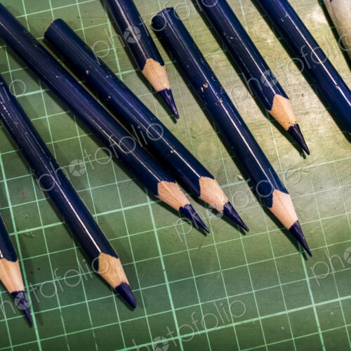 High angle close up of sharpened blue pencils on green cutting mat.