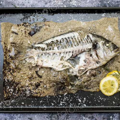 High angle close up of skeleton of grilled sea bream on baking tray. High angle close up of skeleton of grilled sea bream on baking tray.