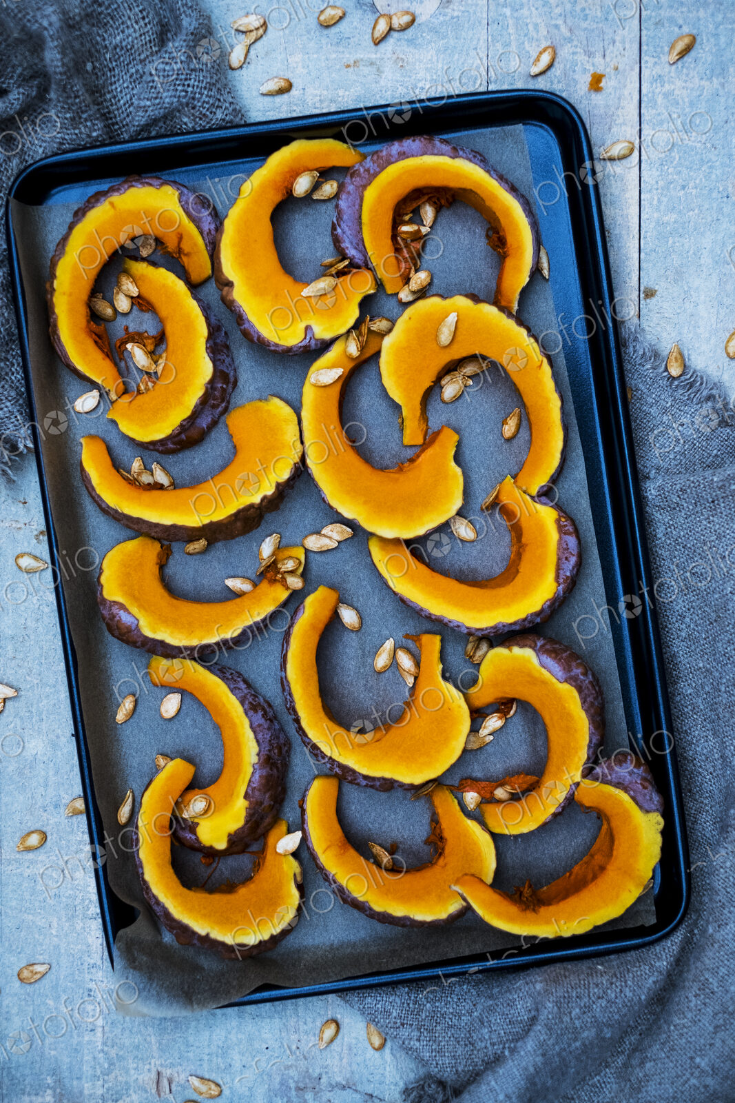 High angle close up of slices of pumpkin on a baking tray.