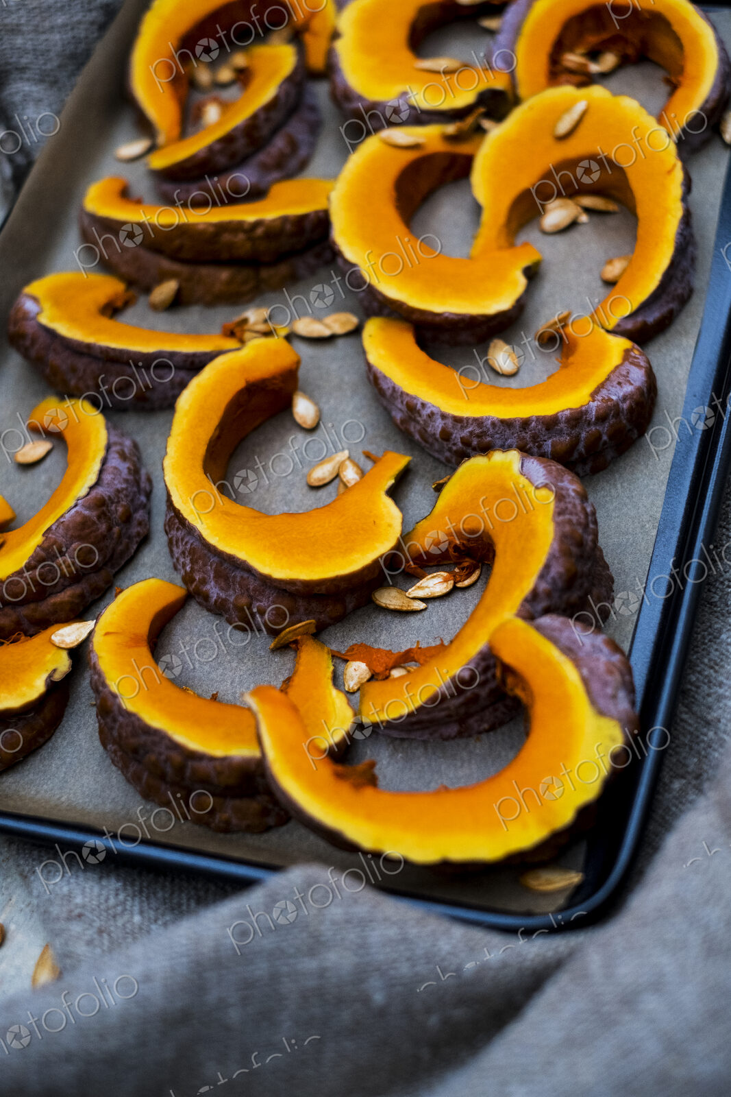 High angle close up of slices of pumpkin on a baking tray.