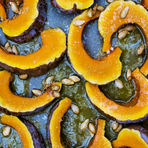 High angle close up of slices of pumpkin on a baking tray. High angle close up of slices of pumpkin on a baking tray.