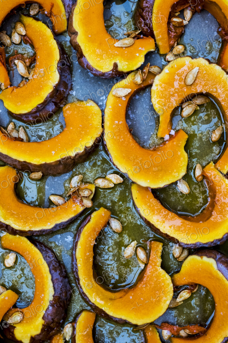 High angle close up of slices of pumpkin on a baking tray.