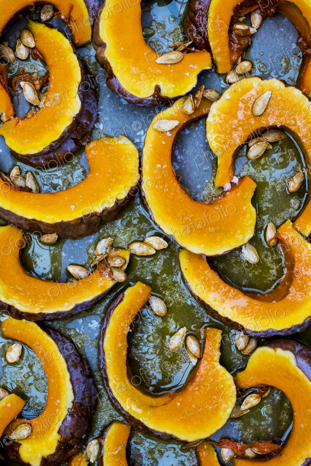 High angle close up of slices of pumpkin on a baking tray.